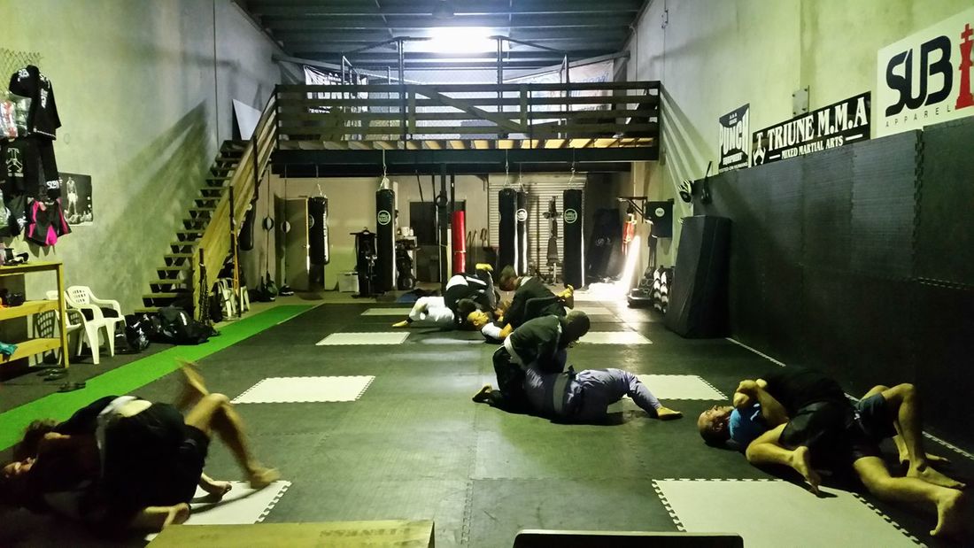 Adults drilling and rolling in the gym at night